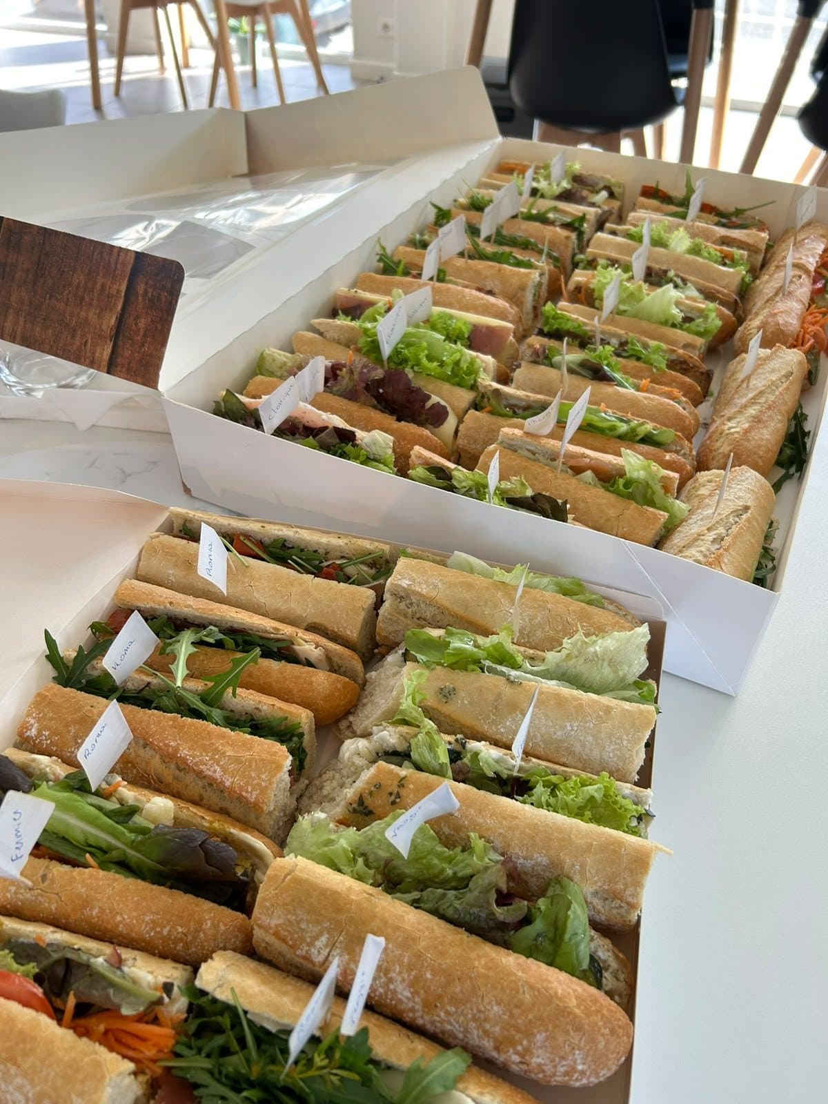 Des baguettes garnies de crudités et de charcuterie, rangées dans leur boîte.