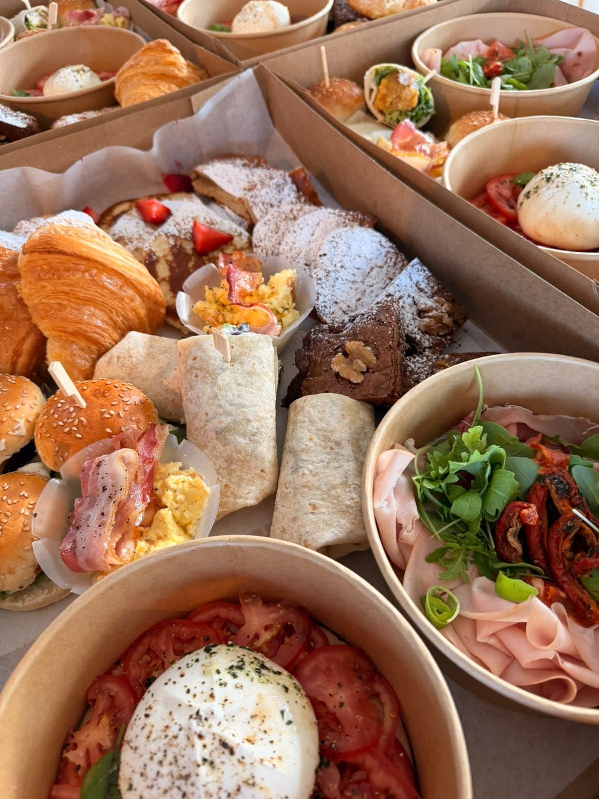 Une box de brunch garnie de wraps, de saumon et d'un bol de burrata.