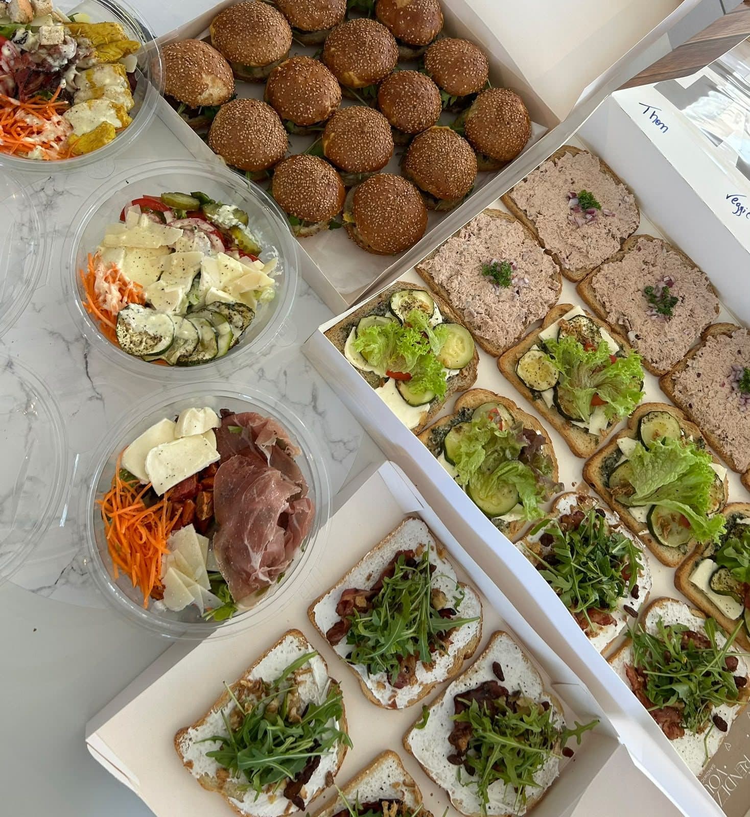 Un plateau de canapés et d'arancini, à côté de deux salades.