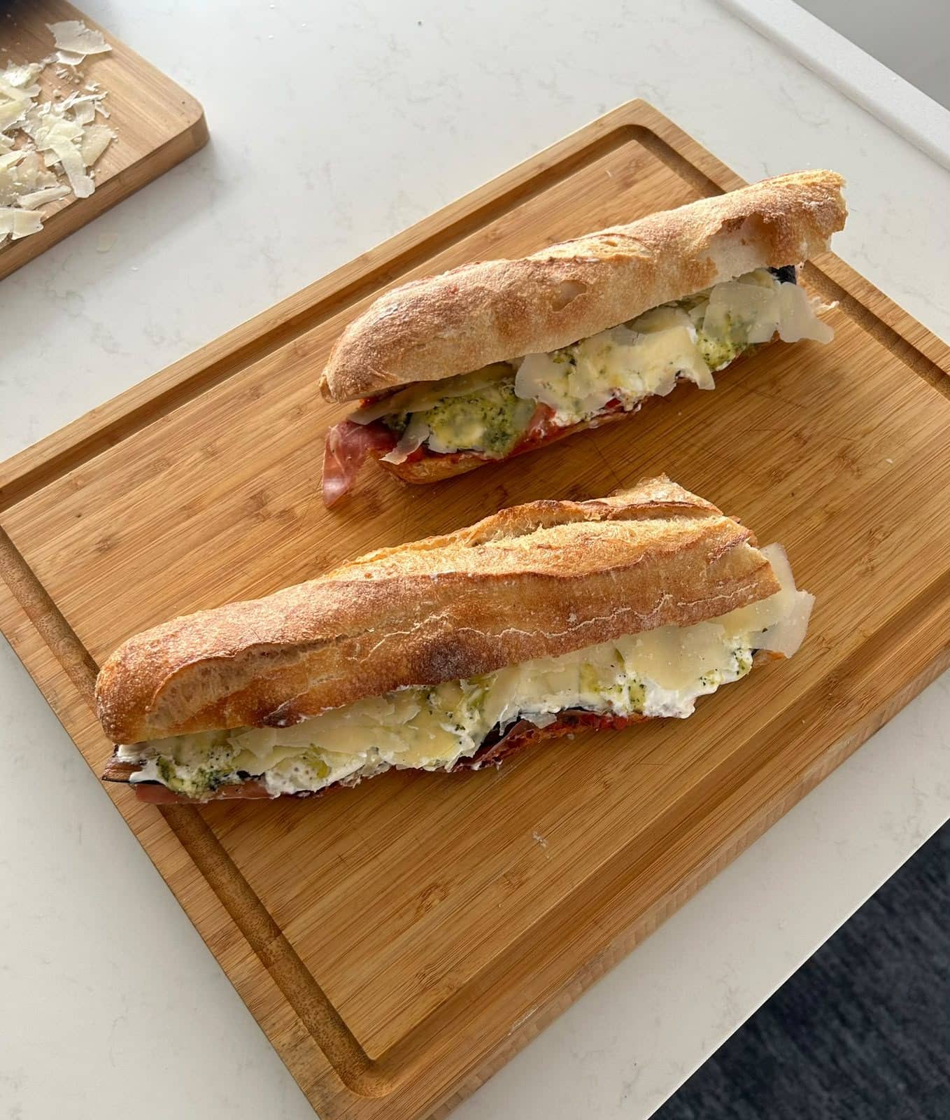 Un sandwich au pain frais, coupé en deux et garni, posé sur une planche en bois.